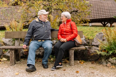 Mann und Frau sitzen auf Gartenbank und unterhalten sich über Entlastung