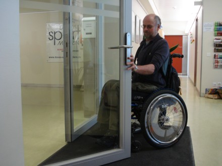 Mann im Rollstuhl öffnet Tür in Ergotherapie